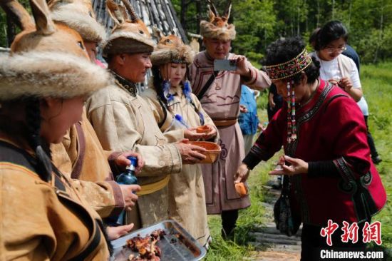 6月18日，鄂伦春猎民身着节日的盛装，为游客献上下马酒。　中新社记者 张玮 摄